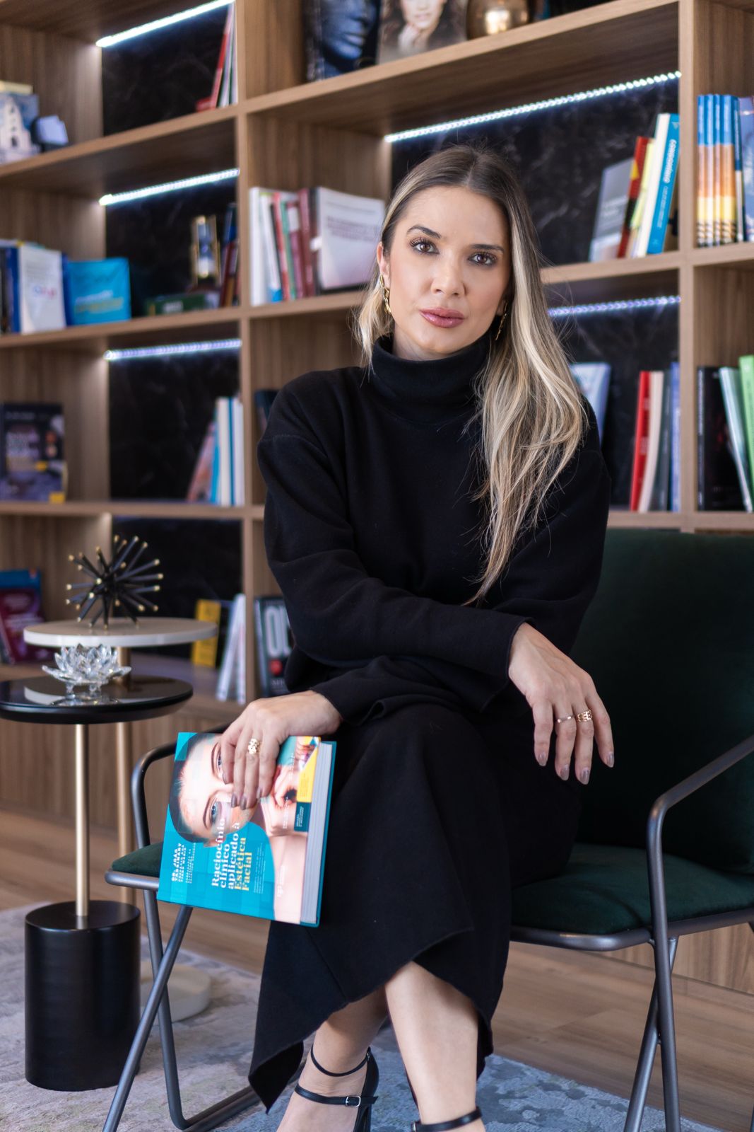 Ana Lucia Bittencourt em seu escritório, com livro técnico